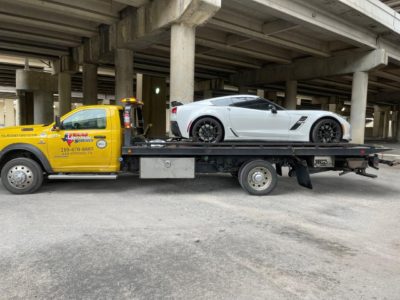 Rayco tow truck towing a white sports car